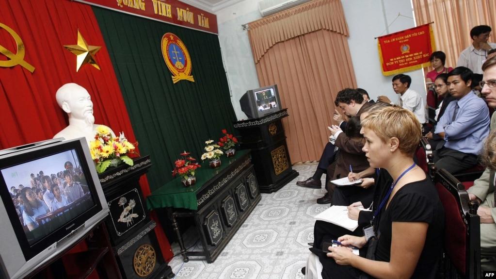 Các nhà báo và đại diện ngoại giao tham dự một phiên tòa xét xử Linh mục bất đồng chính kiến Nguyễn Văn Lý tại một tòa án ở Huế năm 2007 qua màn hình TV trong khuôn viên tòa án.