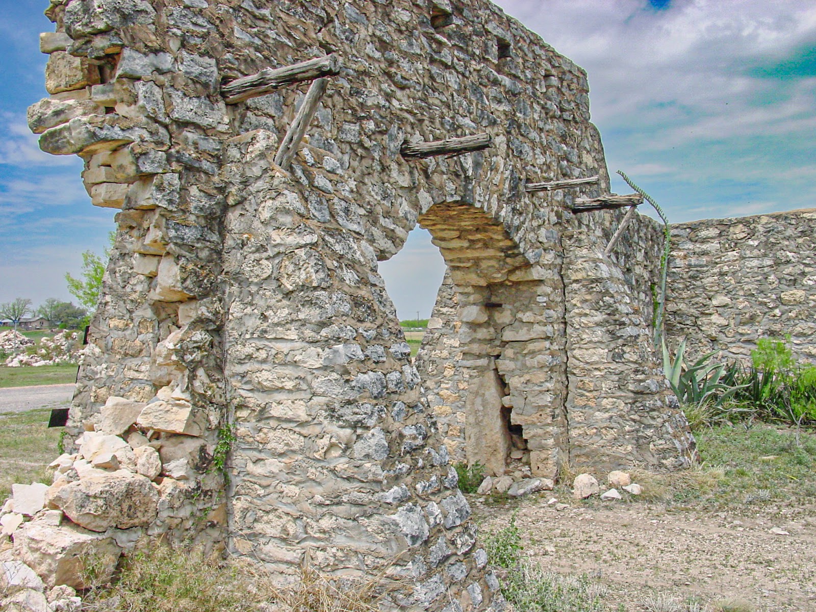 The ruins of an old fieldstone structure with an arched entrance and fallen walls. 