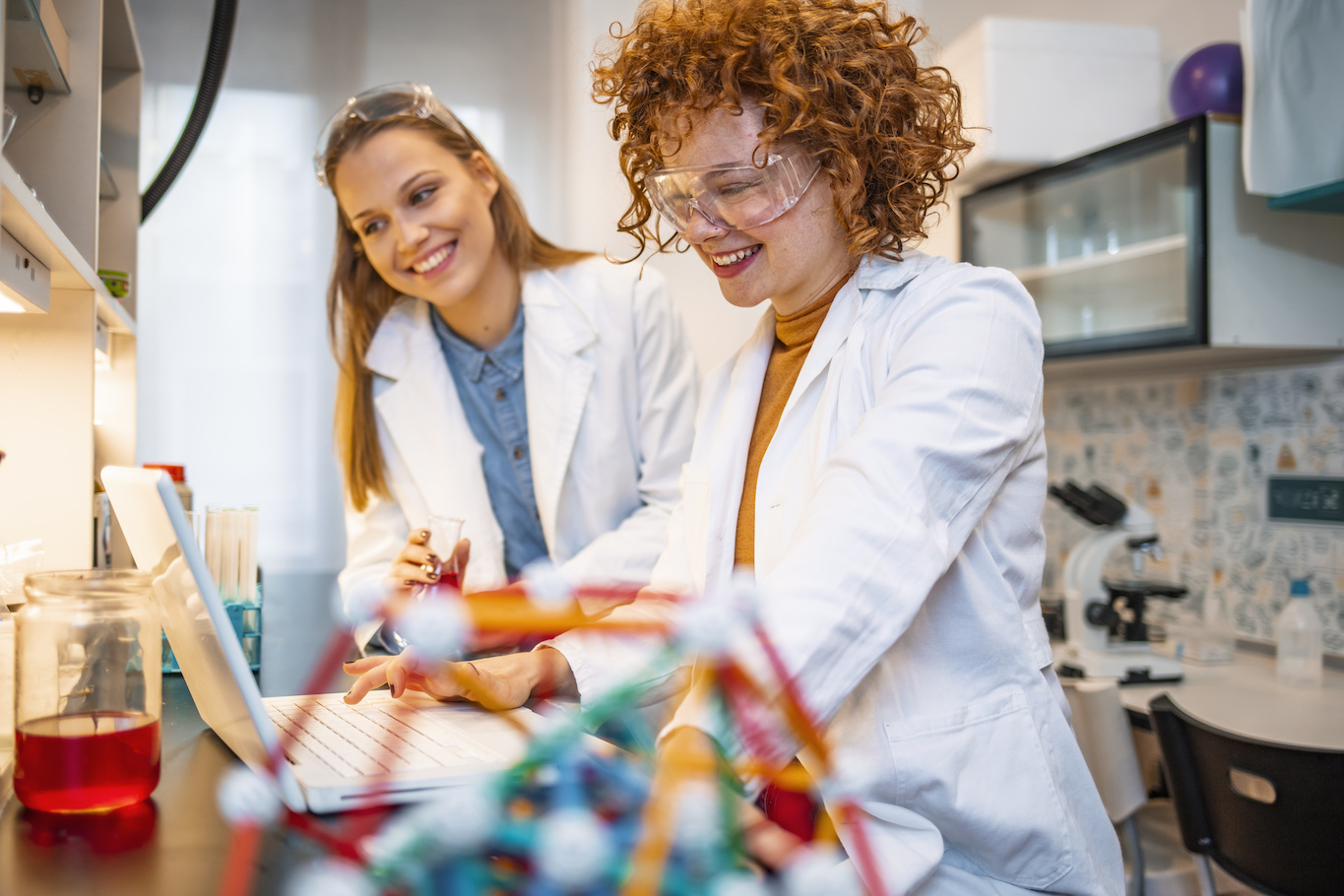 two smiling women wearing lab coats