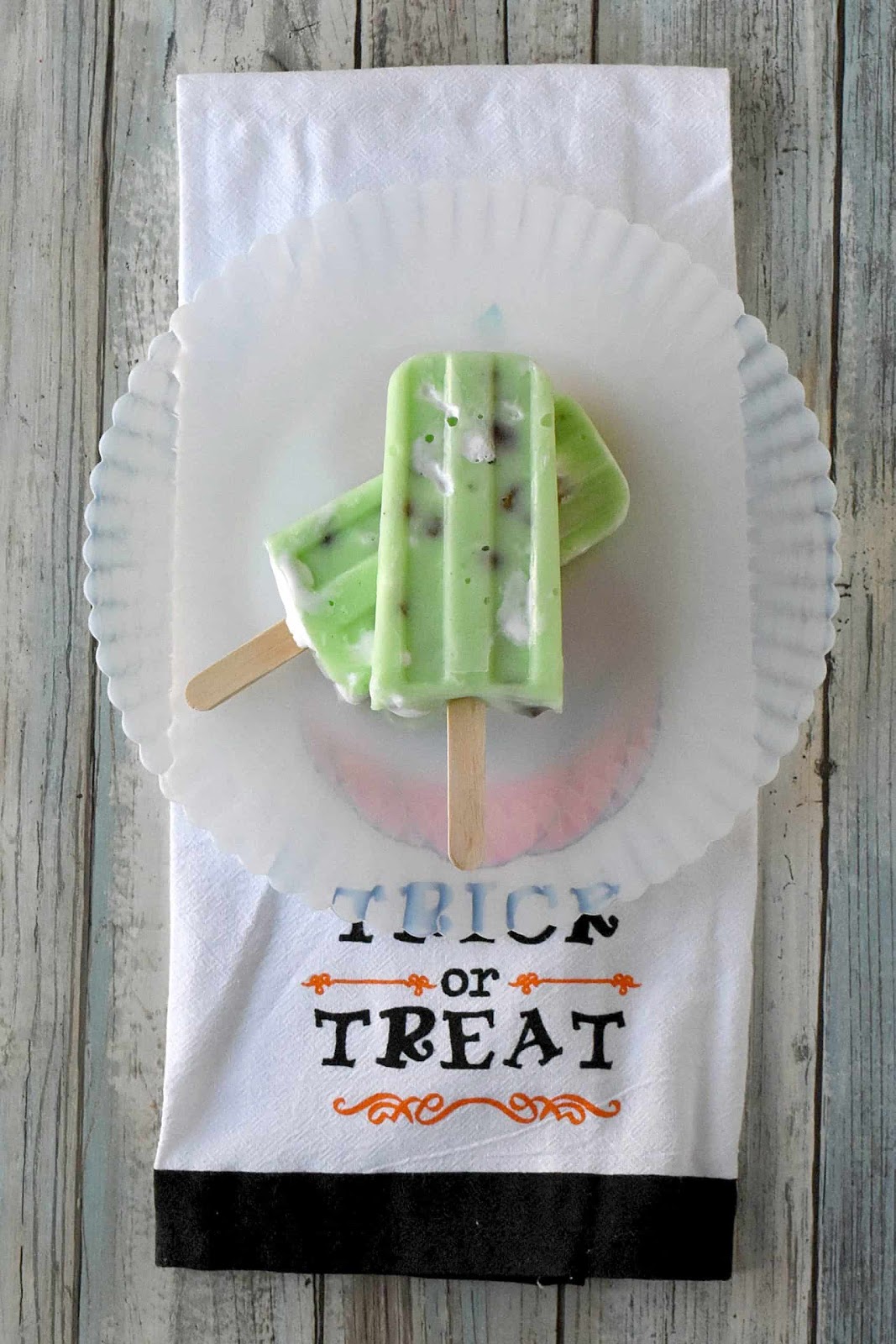 Witch themed popsicles on a white plate.