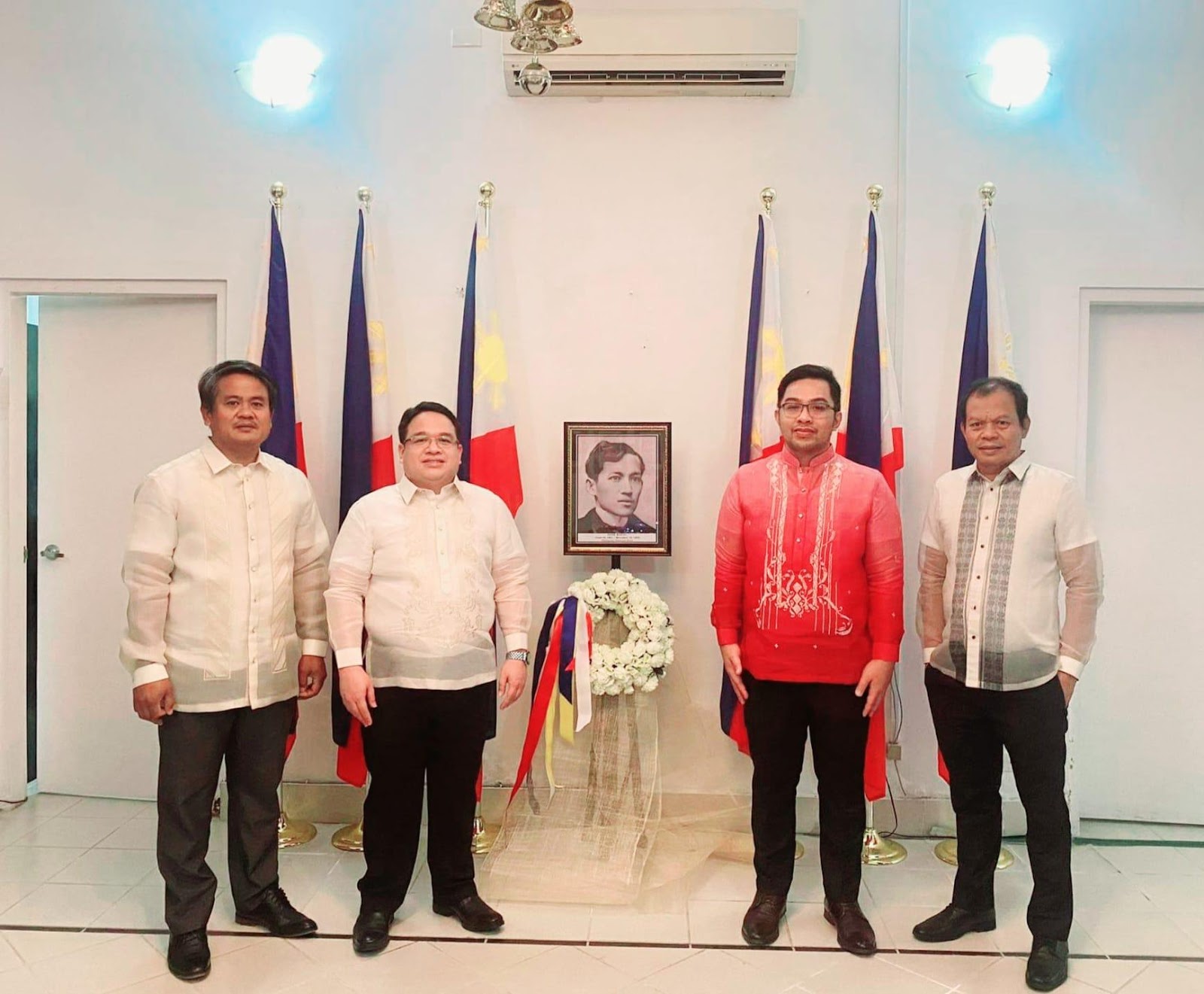 A group of men posing for a photo in front of flags

Description automatically generated