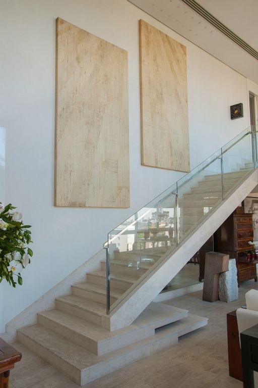 Escada reta com degraus revestidos de porcelanato claro igual ao do ambiente e proteção de vidro