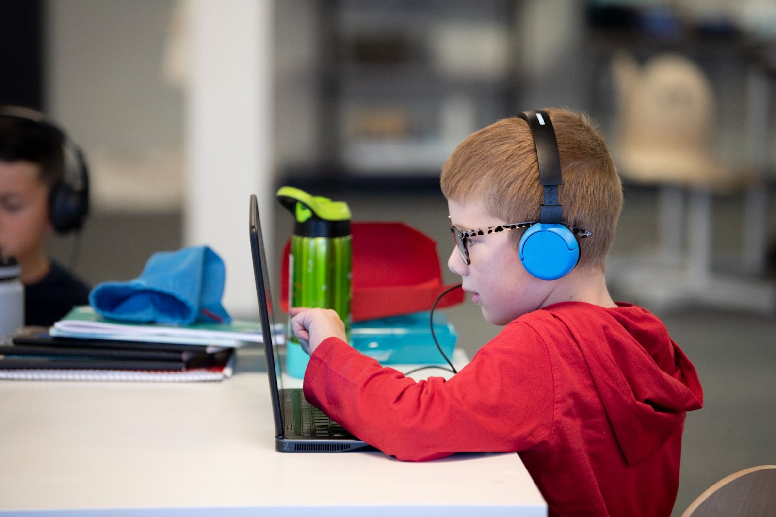 A young child with headphones on doing schoolwork on his computer