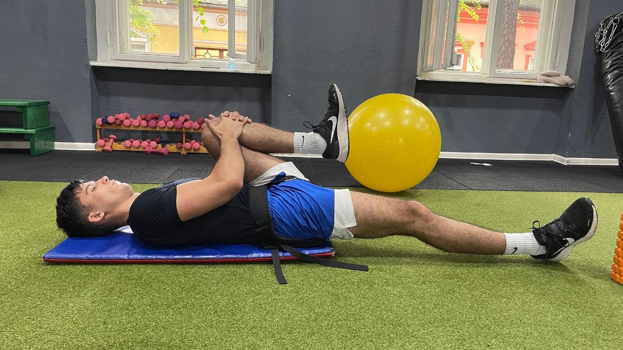 Vanja performs iliopsoas stretch exercise for lower back pain in the commercial gym setup.