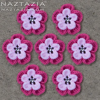 seven pink crocheted flowers on gray background