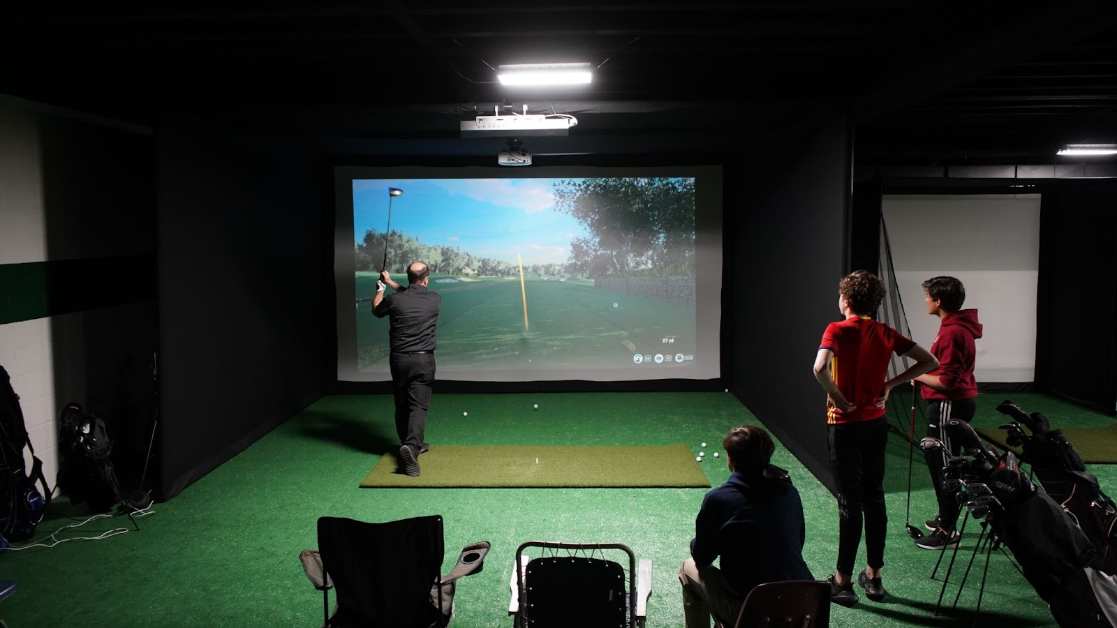 Students and coach playing on golf simulator