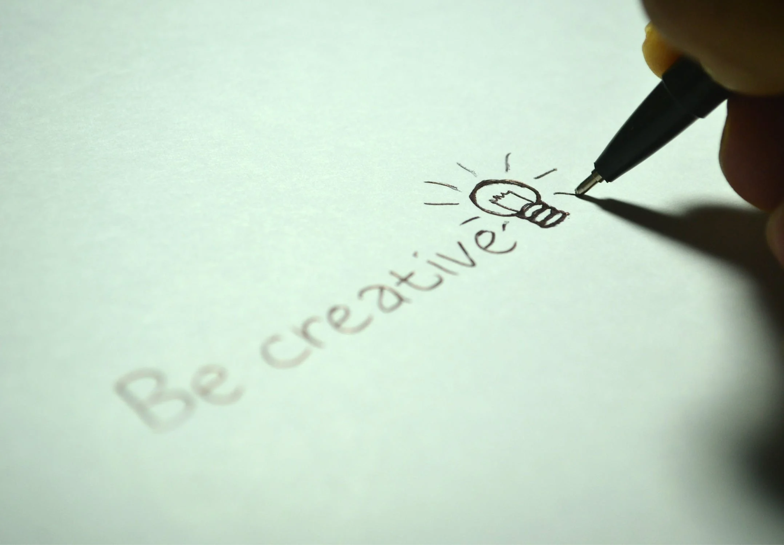 a ball point pen writing the phrase "Be Creative" with blank in