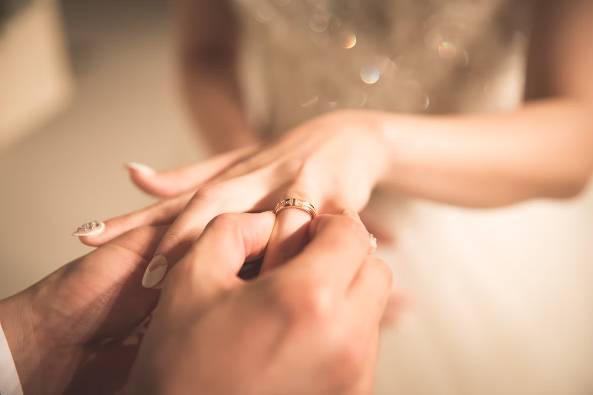 A man putting a wedding ring on the ring finger of a woman