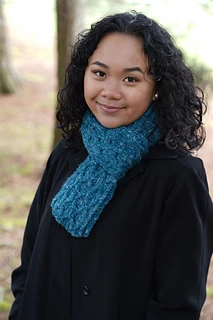 woman wearing a shorter blue reversible knit scarf outside