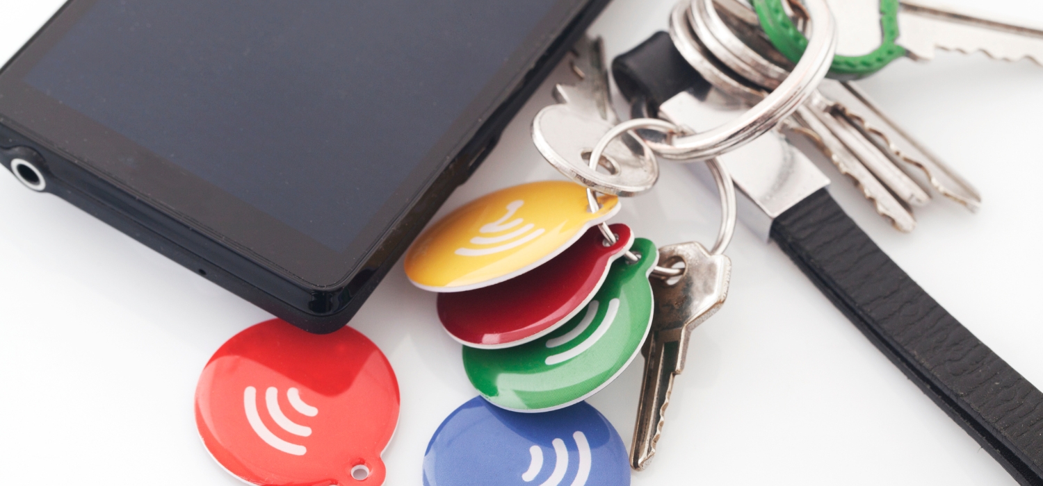 A Blue Red Yellow Green NFC tag lay on the table along with a key and laptop belonging to an event organizer responsible for making NFC Wristbands for Events from GOTAP.