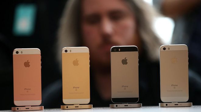 iPhones on display with man in background