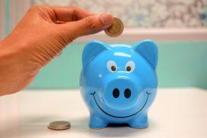 Putting a coin in a piggy bank, representing financial tips to use after buying a home in NYC.