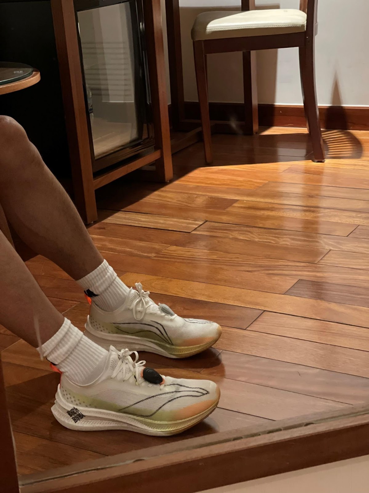 A person's legs in white socks and white socks on a wooden floor

Description automatically generated