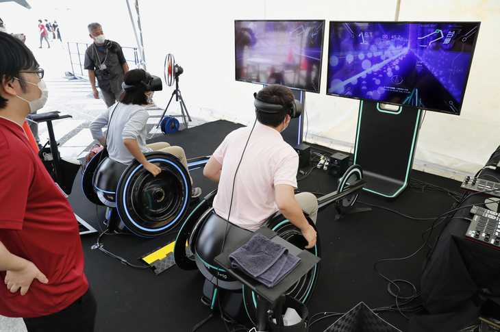 体験イベントで、専用ゴーグルを着けてパラ陸上用の車いすを操作する参加者。仮想現実でパラアスリートの身体能力を感じた＝２０日午前、東京都世田谷区の駒沢オリンピック公園