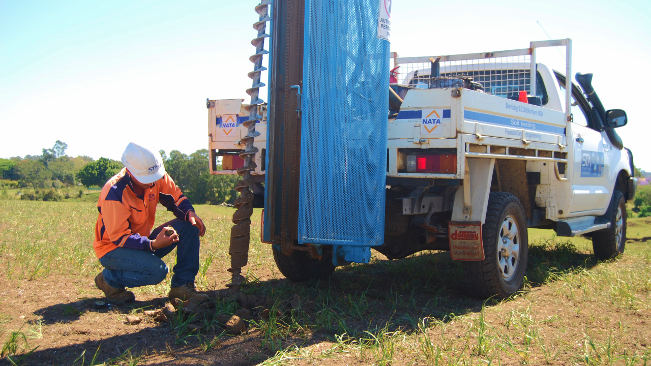 technician crumbling soil in hands beside 4wd vehicle