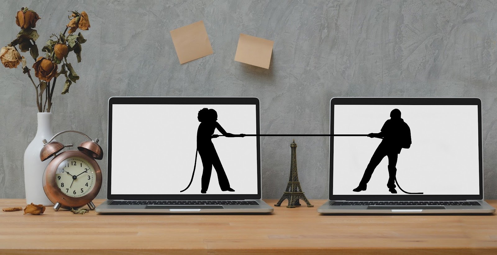 A picture of two laptop computers. There's a silhouette of a woman on the left screen and a  silhouette of a man on the right screen. They're having a tug of war between the two screens.