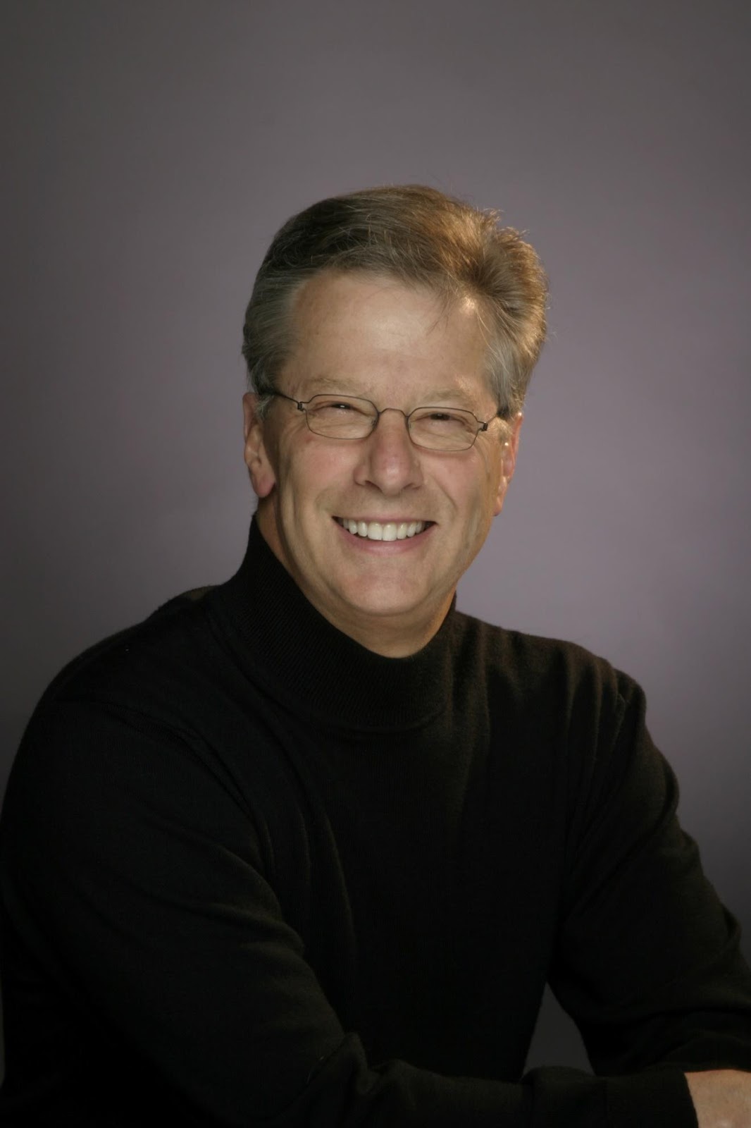 A person wearing glasses and a black turtleneck

Description automatically generated