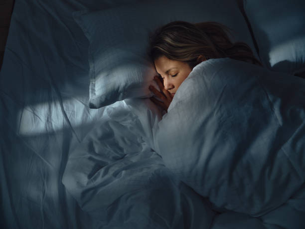 A woman sleeping on white sheets and daylight coming from the tiny window.