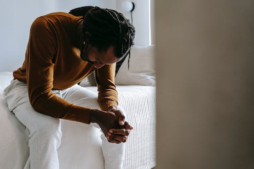 Free Desperate black man sitting on bed in deep thoughts Stock Photo
