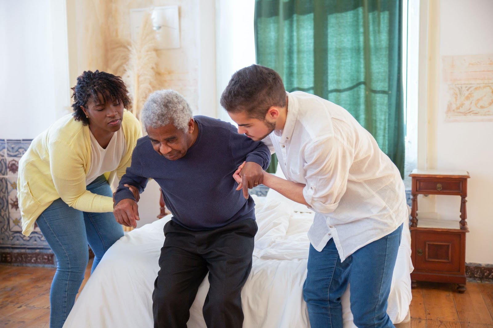 Two nursing home staff members helping a senior resident to sit
