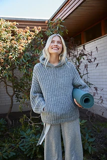 lady wearing hoodie outside with yoga mat