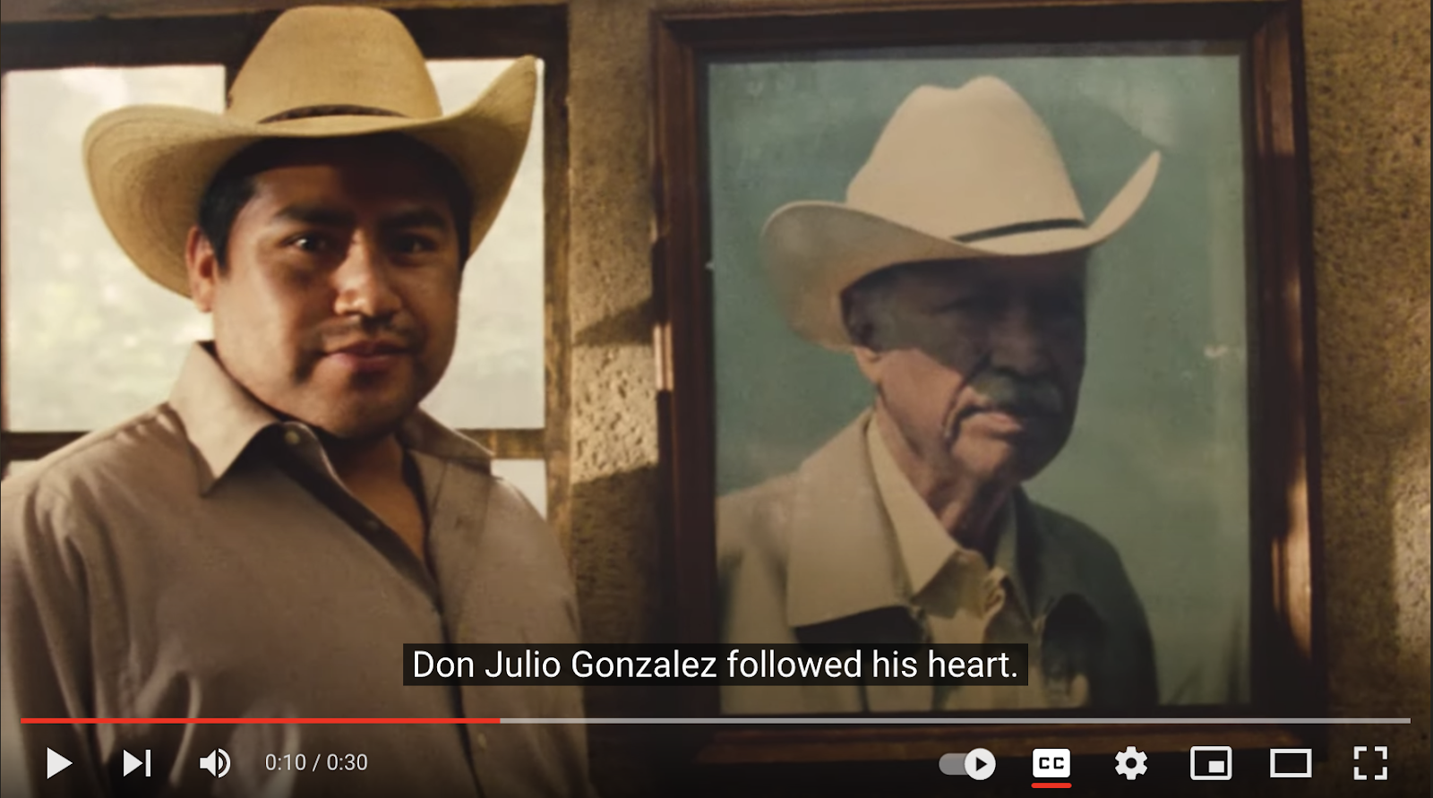 Screenshot of traditional marketing commercial repurposed as YouTube video. Man wearing a cowboy hat stands next to framed photo of Don Julio (namesake of brand) wearing a cowboy hat.