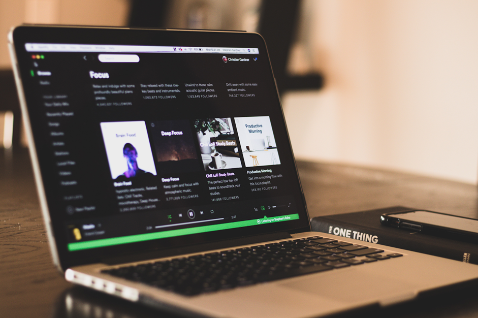 A laptop user using Spotify music.