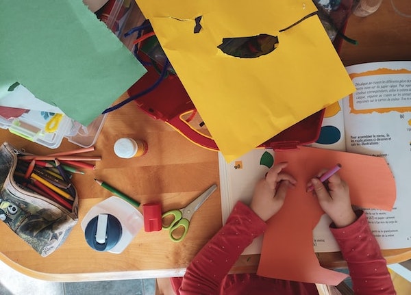 A child doing arts and crafts coloring with a crayon. 