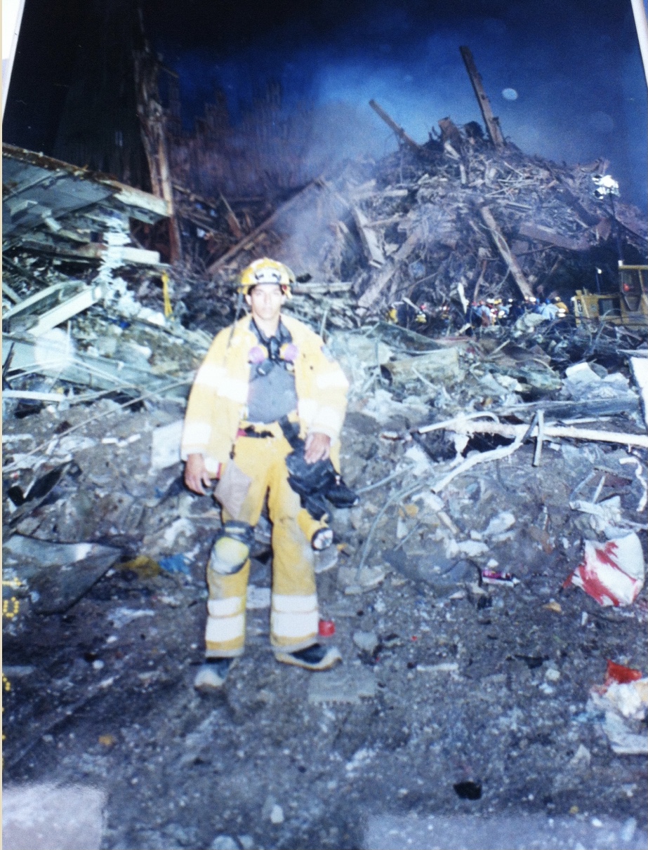A first responder stands on top a pile of rubble