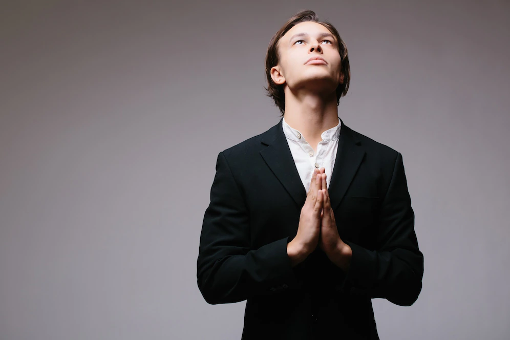 a man dressed in a suit saying his prayers 