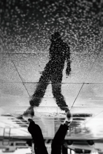 shadow of a person walking on rainy tiled floor