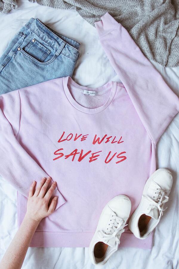 foto de um look na cama com um moletinho escrito "Love will save us", uma calça jeans e um tênis