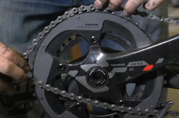 Gently place the back knot of the tangled mountain bike chain onto the chainring.