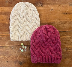 two cable knit hats on wooden background