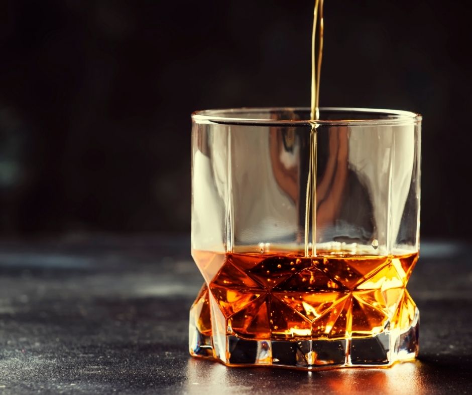 whiskey pouring into a glass to represent glassware for a bourbon gift guide