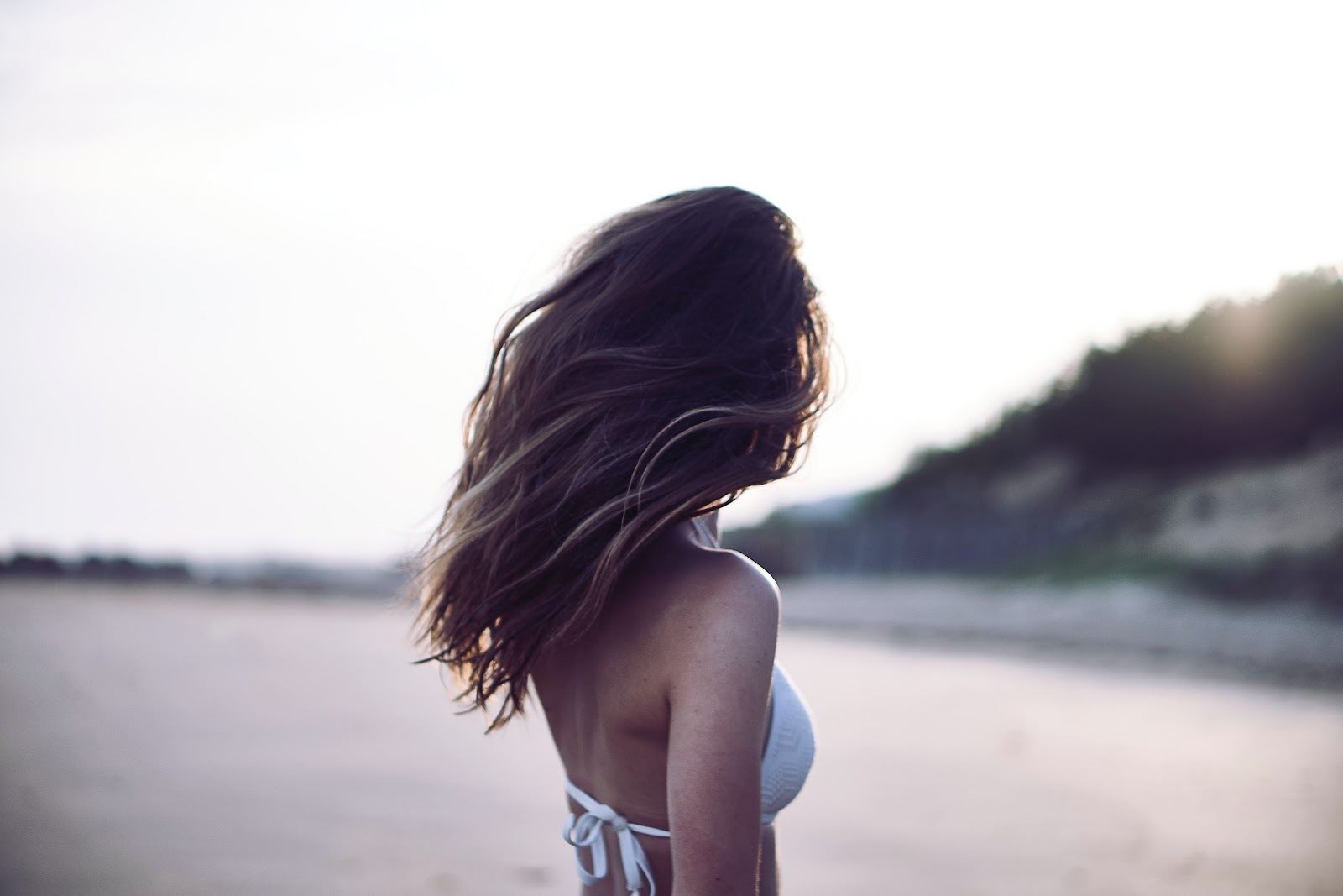 a girl with wavy hair standing on a beach in summers