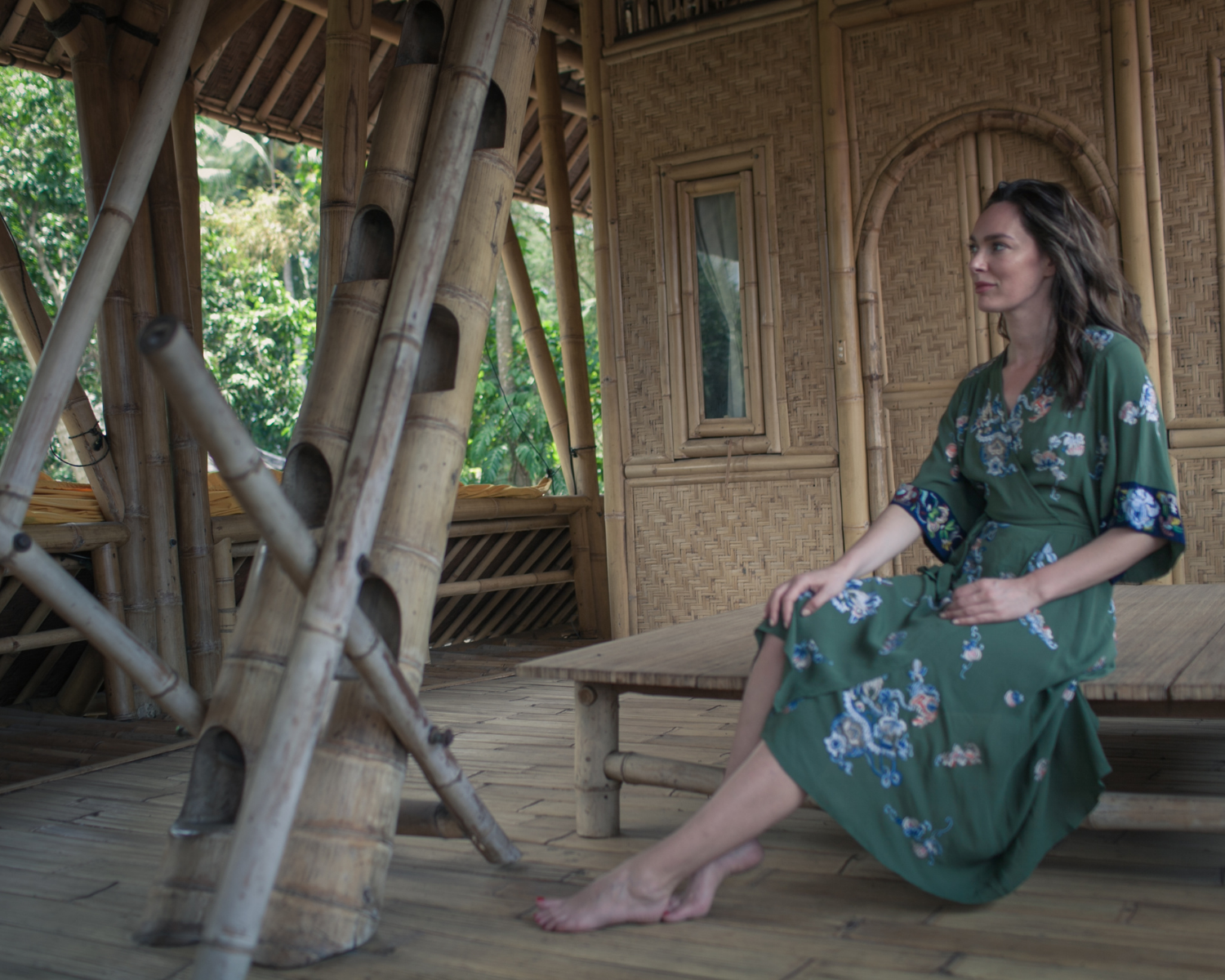 Woman in a green dress sitting in a bamboo hut