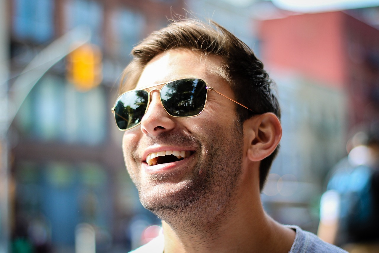 man wearing sunglasses smiling, white teeth, clean teeth