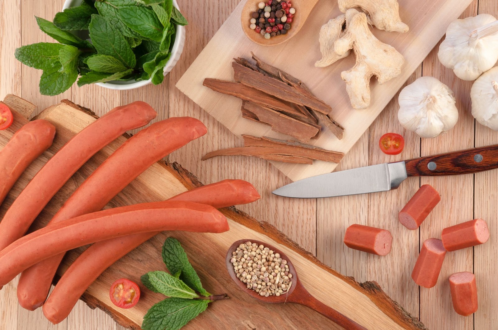 A cutting board with homemade sausages and some vegetables.