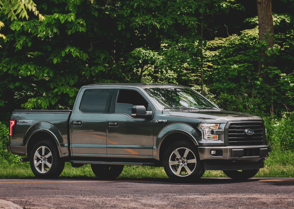 Ford F150 on gravel road in front of green foliage