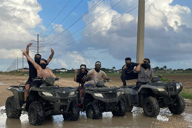 A group of people riding ATVs through muddy terrain
