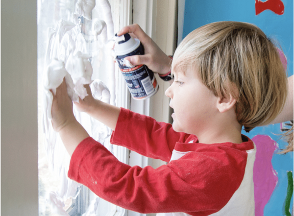 Child drawing in shaving cream on window