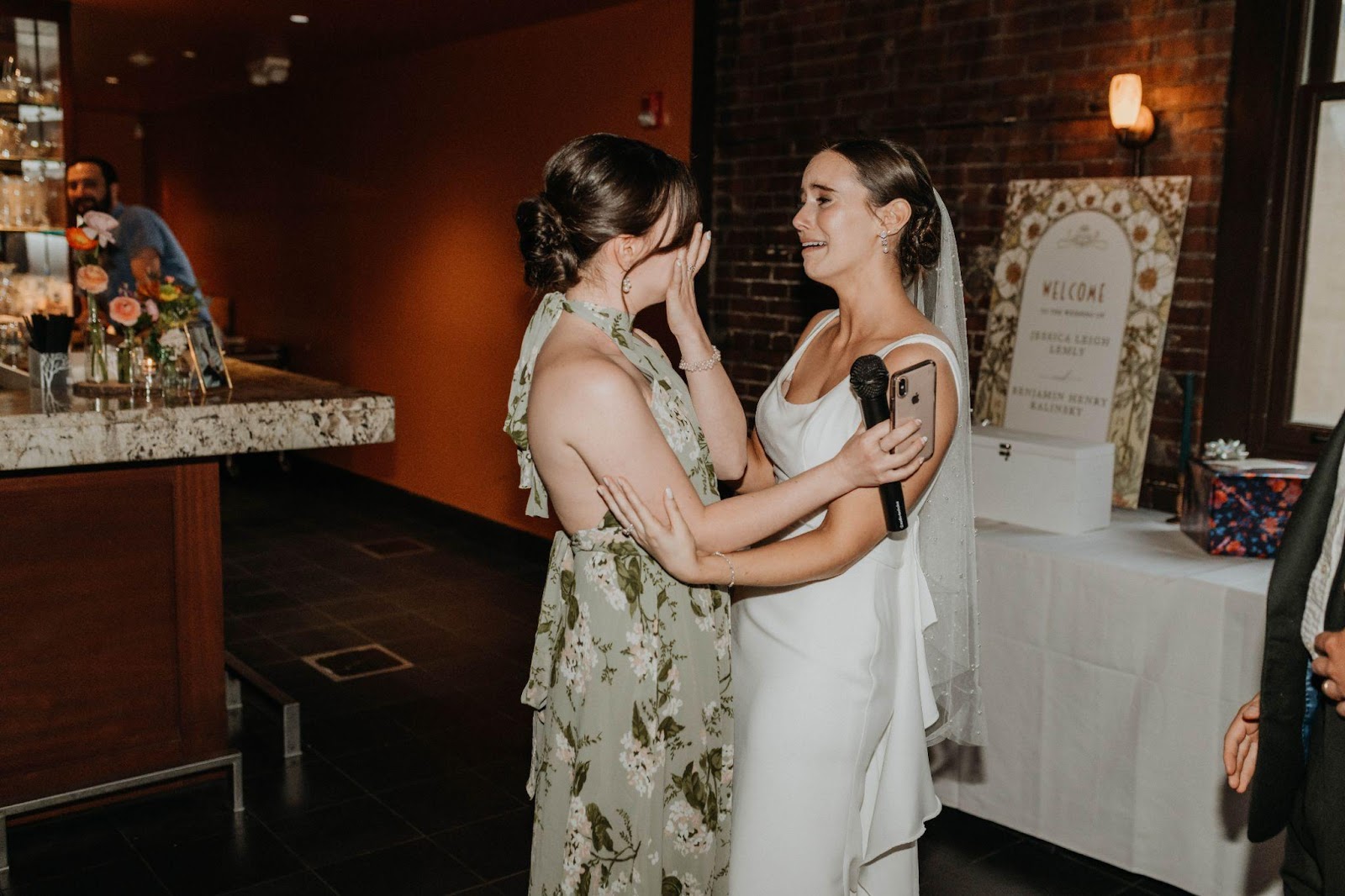 Documentary-style wedding photography captures a bride embracing her maid of honor with tears in her eyes.