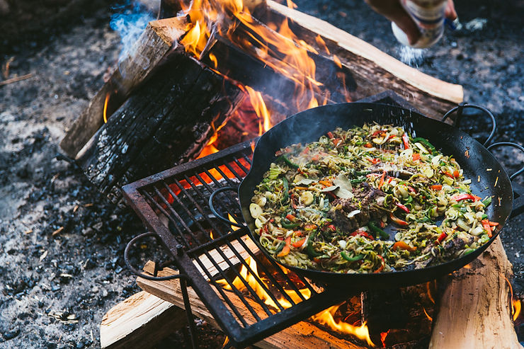 Argentine celebrity Chef Francis Mallmann prepares a feast in a cast iron skillet over an open fire. It looks delicious, but we have no idea what it actually is.