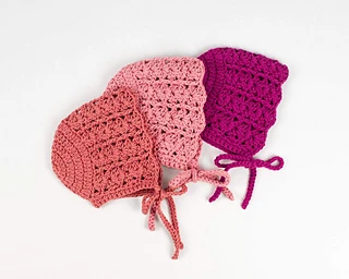 three colors of crochet baby bonnets on white background