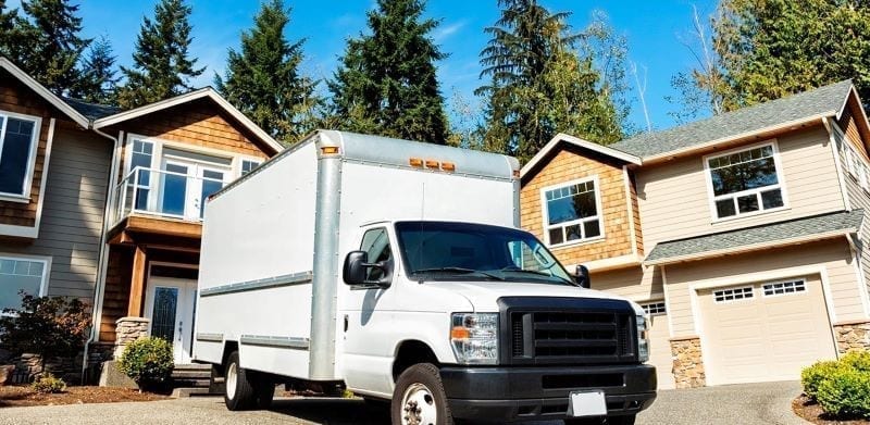 A moving truck is parked outside of a residential home, ready to be loaded.
