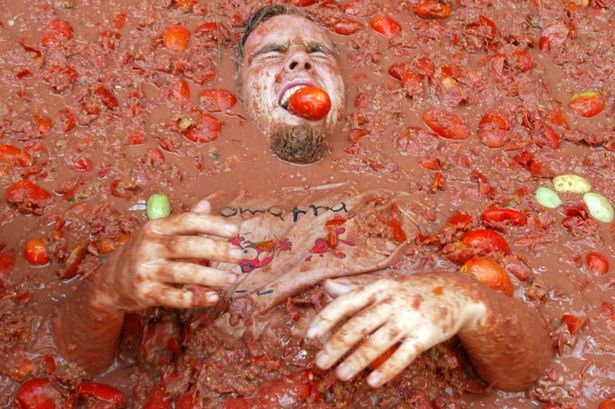 A reveller bites into a tomato during the annual Tomatina in the Mediterranean village of Bunyol