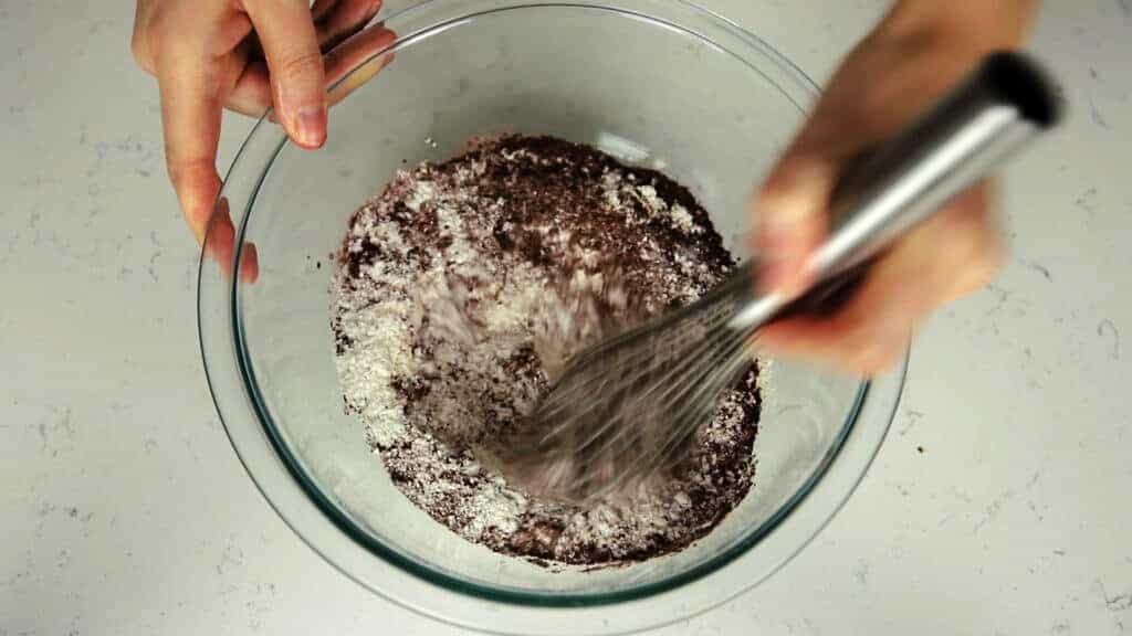hand whisking red velvet drying ingredients together in bowl
