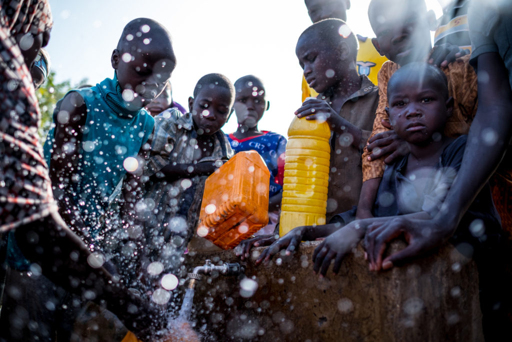 Jovens deslocados internos enchem recipientes com água no acampamento Dalori, em Maiduguri, no estado de Borno, na Nigéria. Foto: UNICEF/Gilbertson