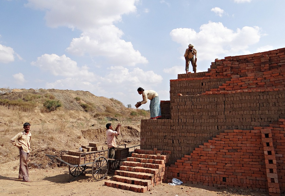 People working on an unfinished masonry wall.